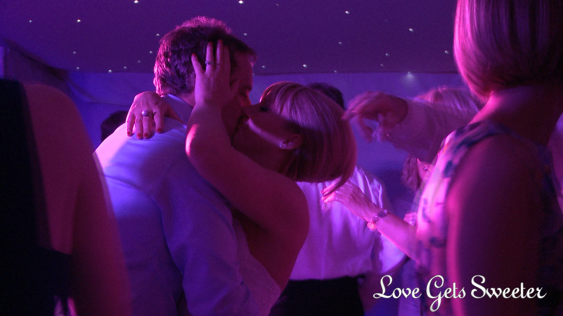 a bride and groom have a passionate kiss on the dancefloor as their guests dance around them during their wedding reception at Combermere Abbey in Cheshire