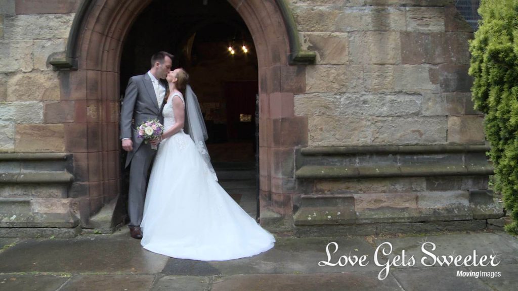 bride and groom kiss under the archway outside church showing off brides bespoke dress