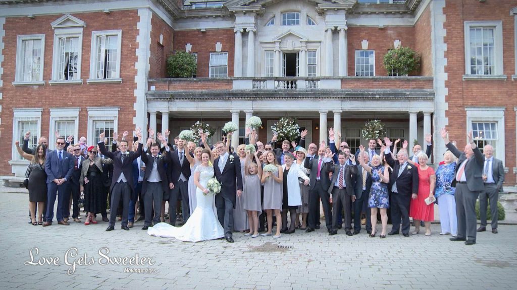 large group shot outside the front of Eaves Hall on wedding video
