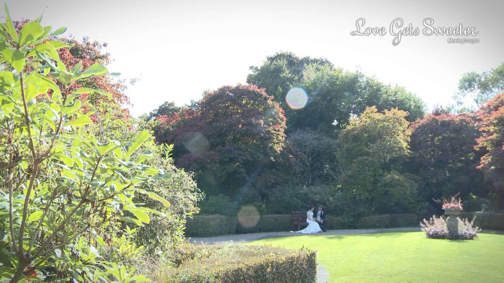 late afternoon sunshine bride and groom on bench in Eaves Hall gardens
