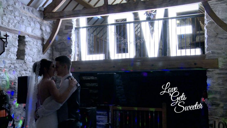 bride and grooms first dance at Plas Isaf country barn in front of giant LOVE letters