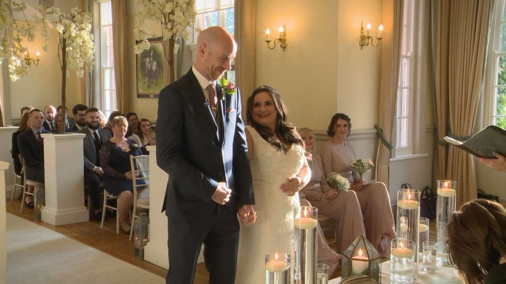 the bride and groom laugh and look relaxed on their wedding video during the ceremony in Cheshire