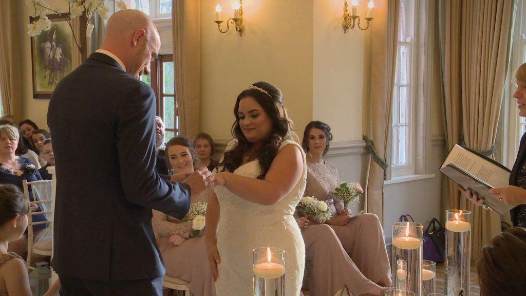 the groom puts the wedding ring on his bride as they say their vows at Nunsmere Hall