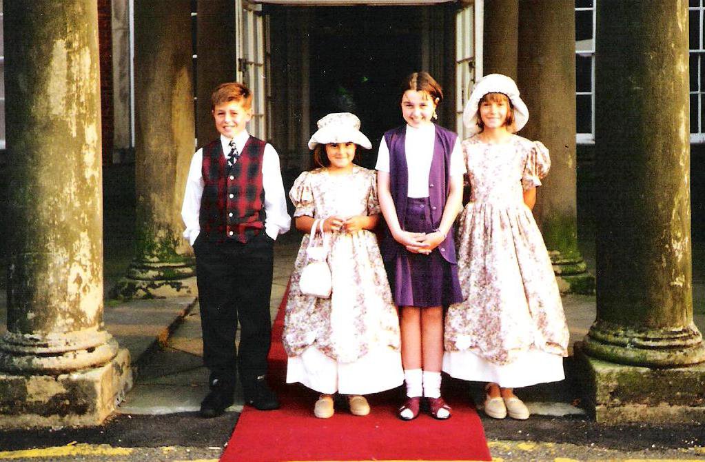 two young bridesmaids or flower girls standing in front of colwick hall with two other children wearing matching flowery dresses and hats from a late 80's or 90s wedding in Nottingham