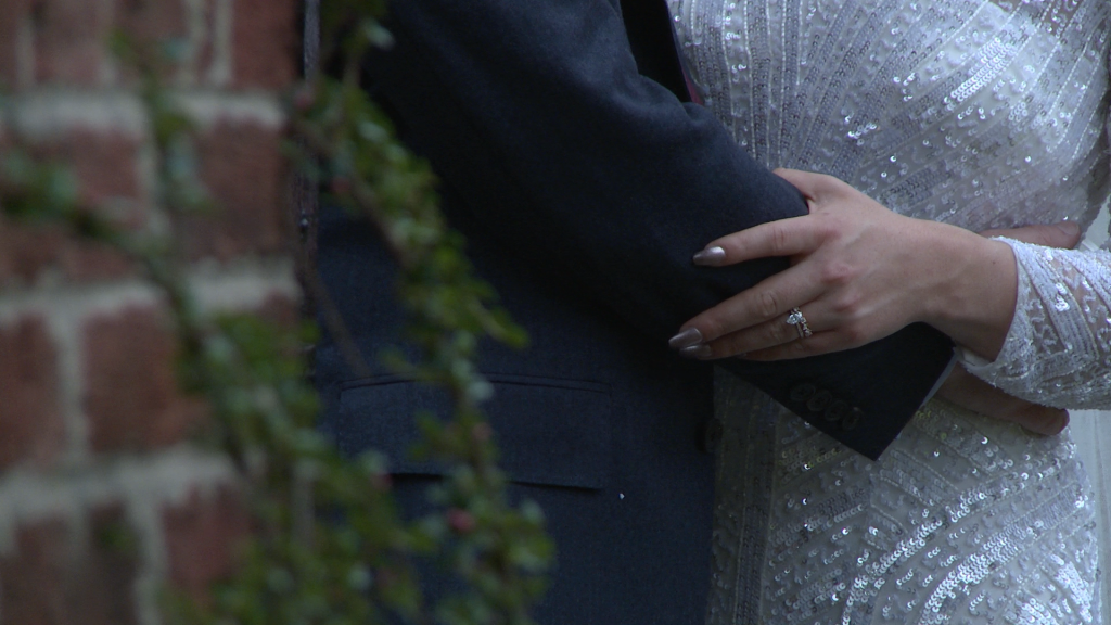 a close up of the brides wedding ring on her hand as she holds her grooms arms