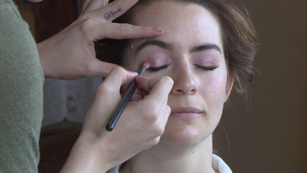 Caitlin Helsby the make up artist applies a pink eye shadow to the brides eyelid