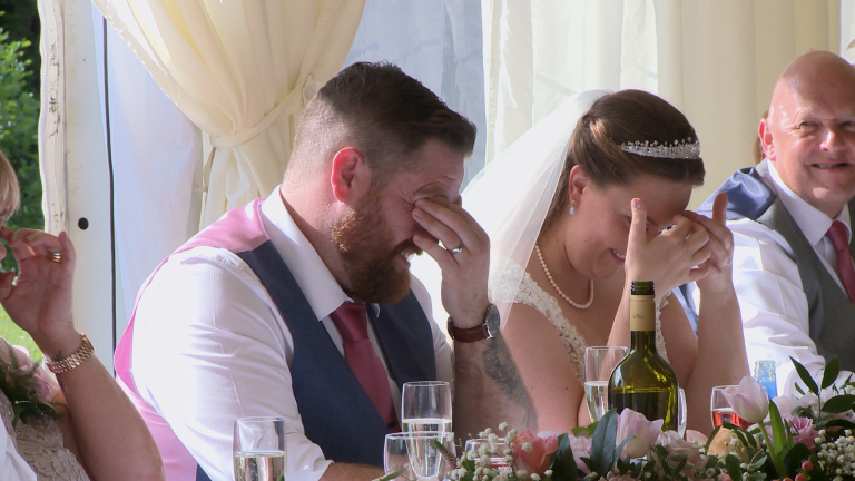 the groom and bride hide their faces in embarrassment during the best man speech