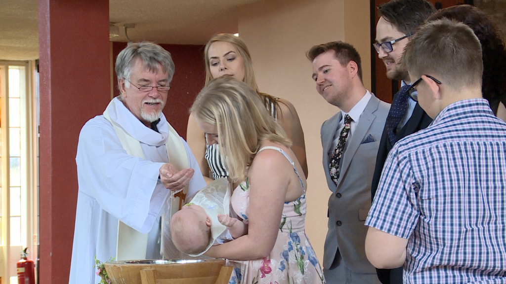 a baby boy gets baptised in front of parents and godparents at a christening st pauls of the cross in Burtonwood