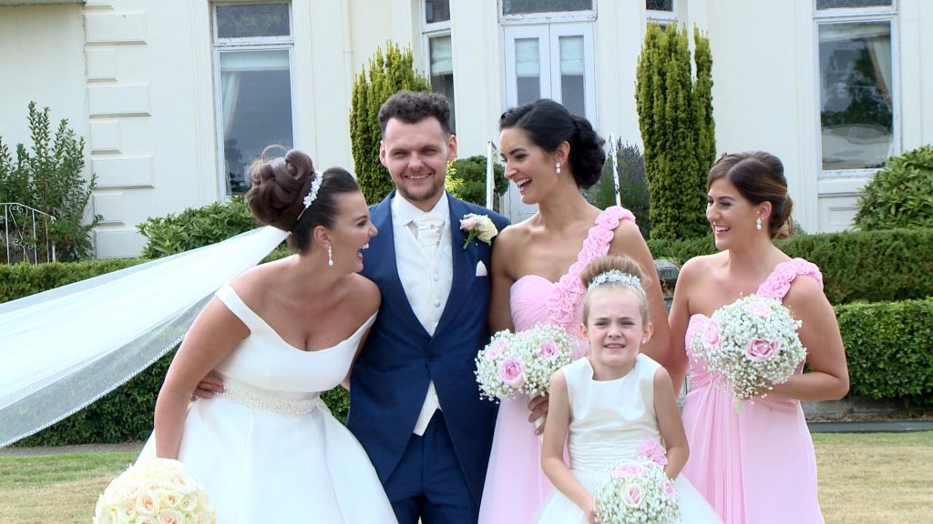 the bride and bridesmaid laugh at each other as the groom stands smiling inbetween as they pose for photos at Thornton manor