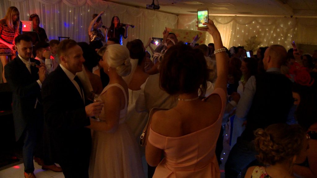 a full dancefloor of wedding guests at Thornton hall hotel in the wirral dancing and singing along with northrn lights band on stage