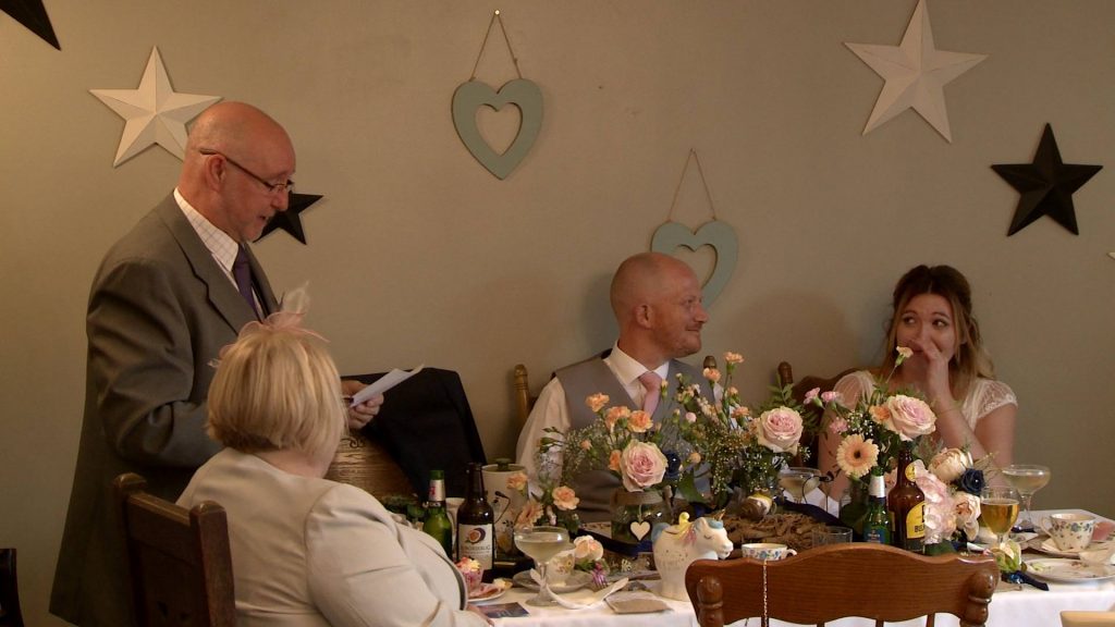 the bride wipes tears away sat at the top table as her dad gives his wedding speech