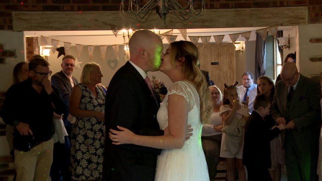 the bride and groom enjoy a kiss during their first dance captured by thr wedding videographer at Abel's Harp in Bromlow 