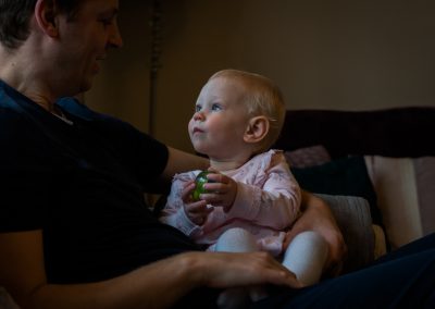 a little girl gazes up towards her dad with her big blue eyes whilst holding a ball. Captured by Love Gets Sweeter family photography and videography in lancashire