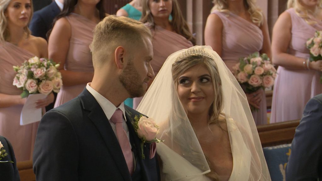 a video still of the bride and groom glancing at each other with a little smile as they get married at Oxton St Saviours church in the wirral