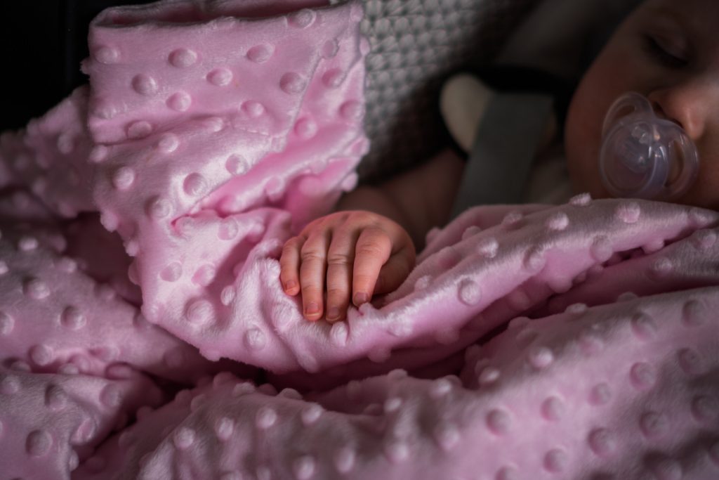 a close up of a little baby girls hand laying gently on a baby pink blanket as she sleeps before her christening in Todmorden