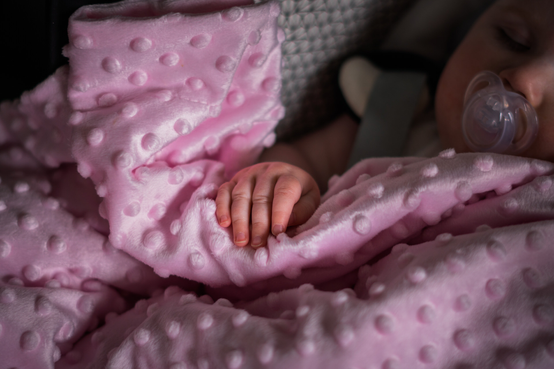 a close up of a little baby girls hand laying gently on a baby pink blanket as she sleeps before her christening in Todmorden