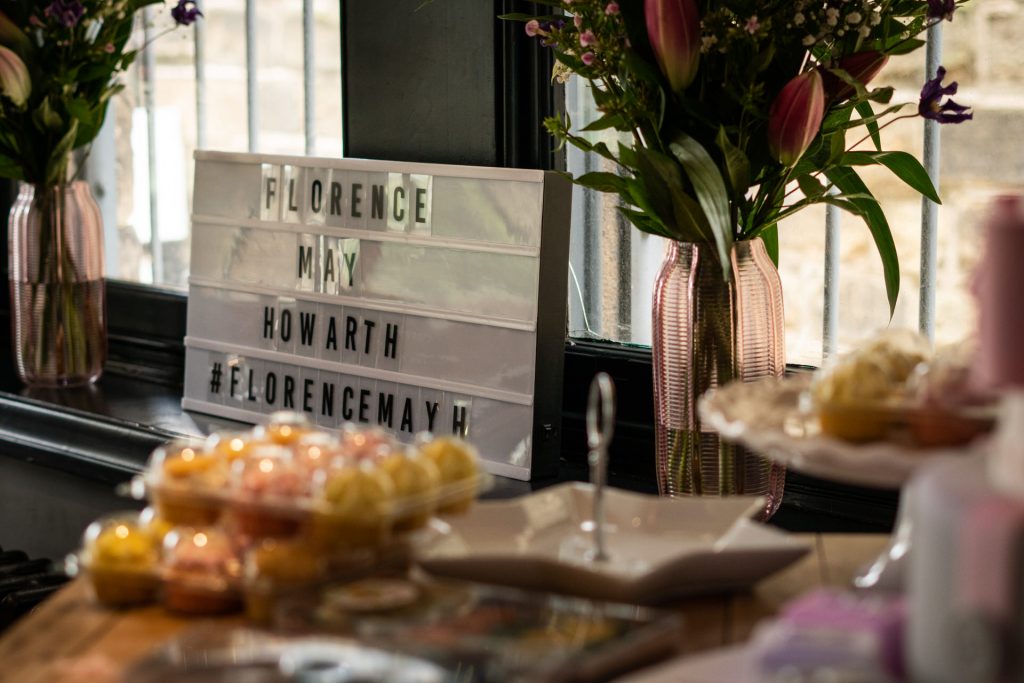a family photographer captures the details at a family blessing and christening at Site Pizzeria in Lancashire with a cake table and sign