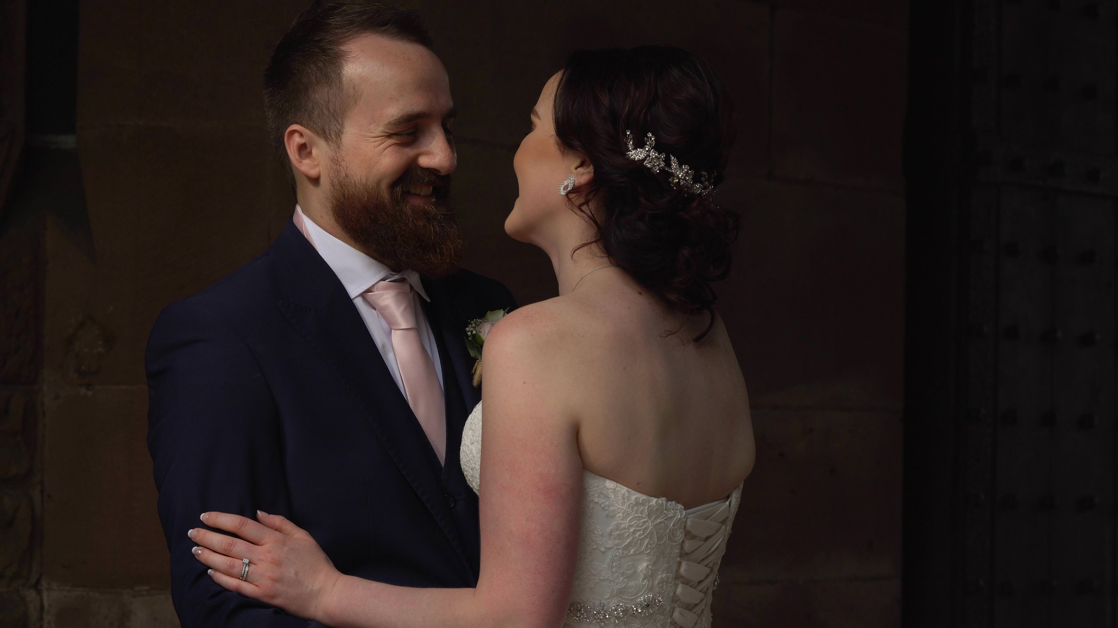 a still from the wedding video of the bride and groom laughing during their couple portraits in the grounds of peckforton castle
