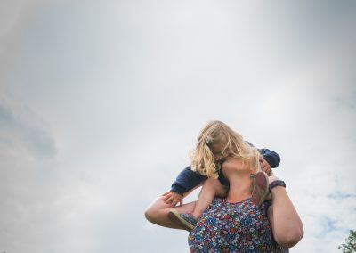a little girl on her mums shoulders leans down and kisses her mum during a family photography shoot in wetherby