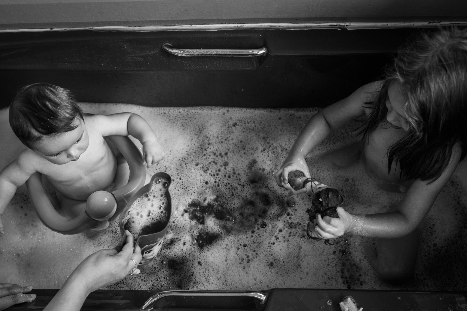 a black and white photograph of siblings in a bath together playing