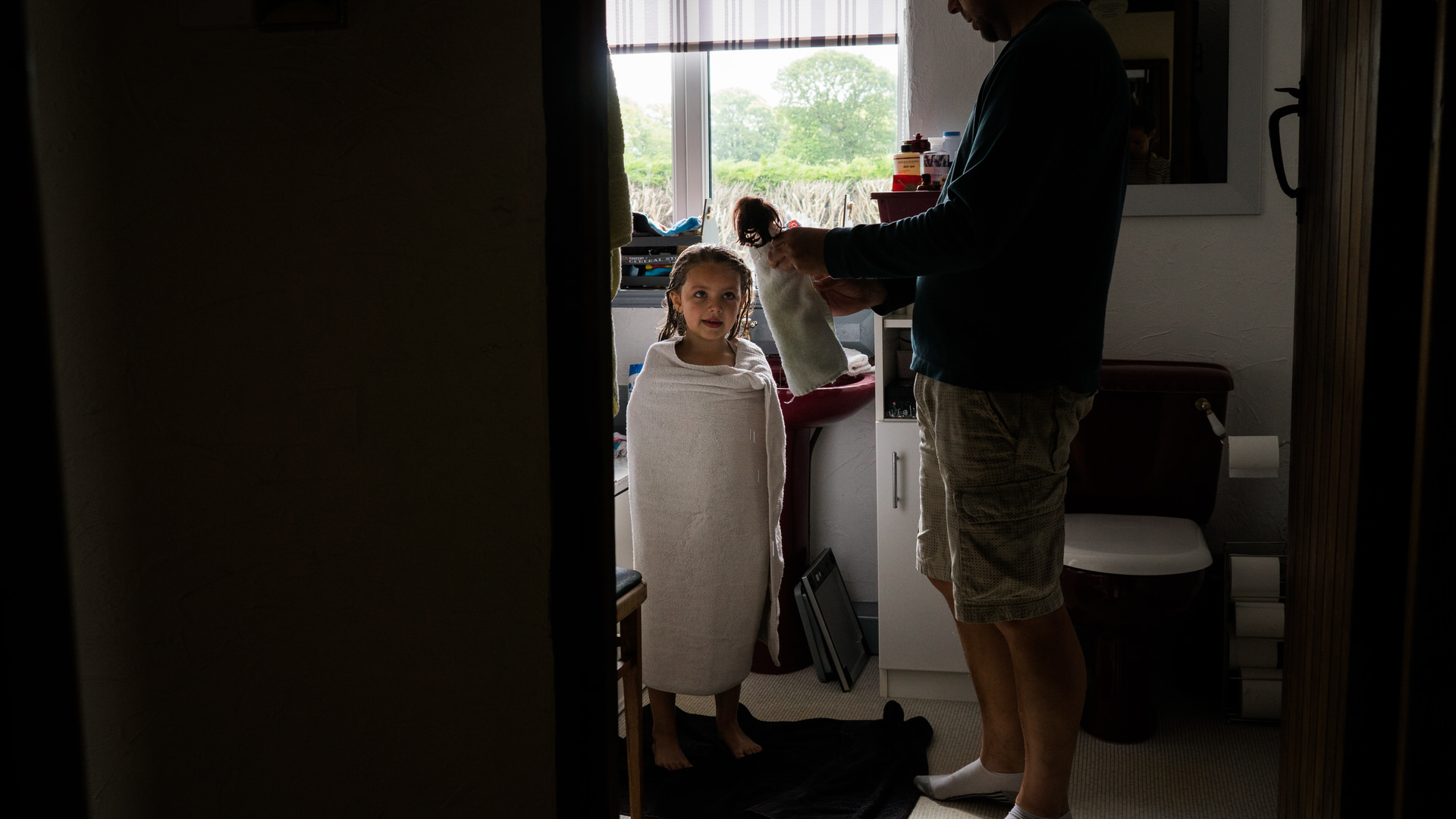 dad wraps up Barbie in a matching towel after a bath during a family photography session