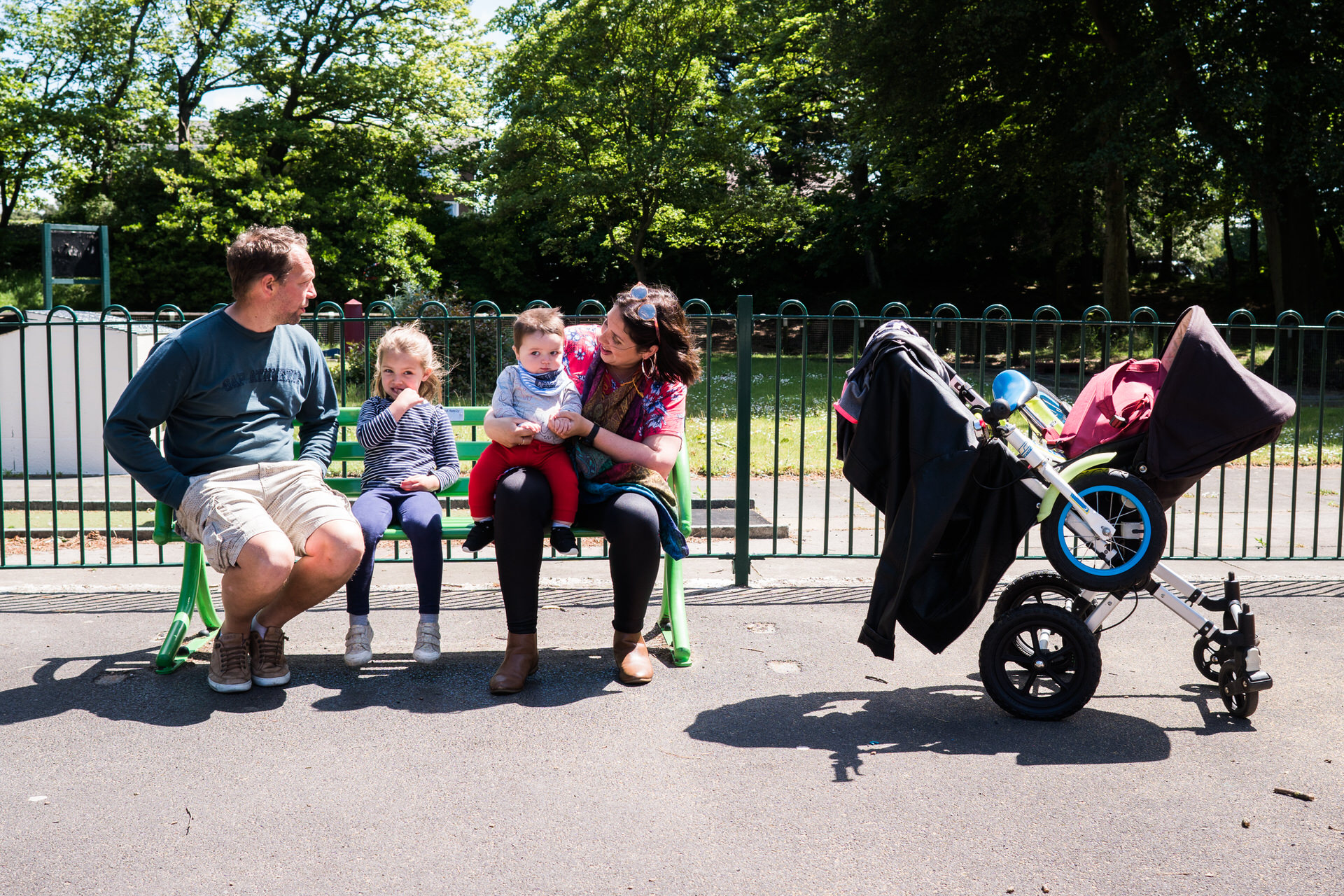 a family of four sit on a bench at Hesketh Park for a day in the life photo shoot