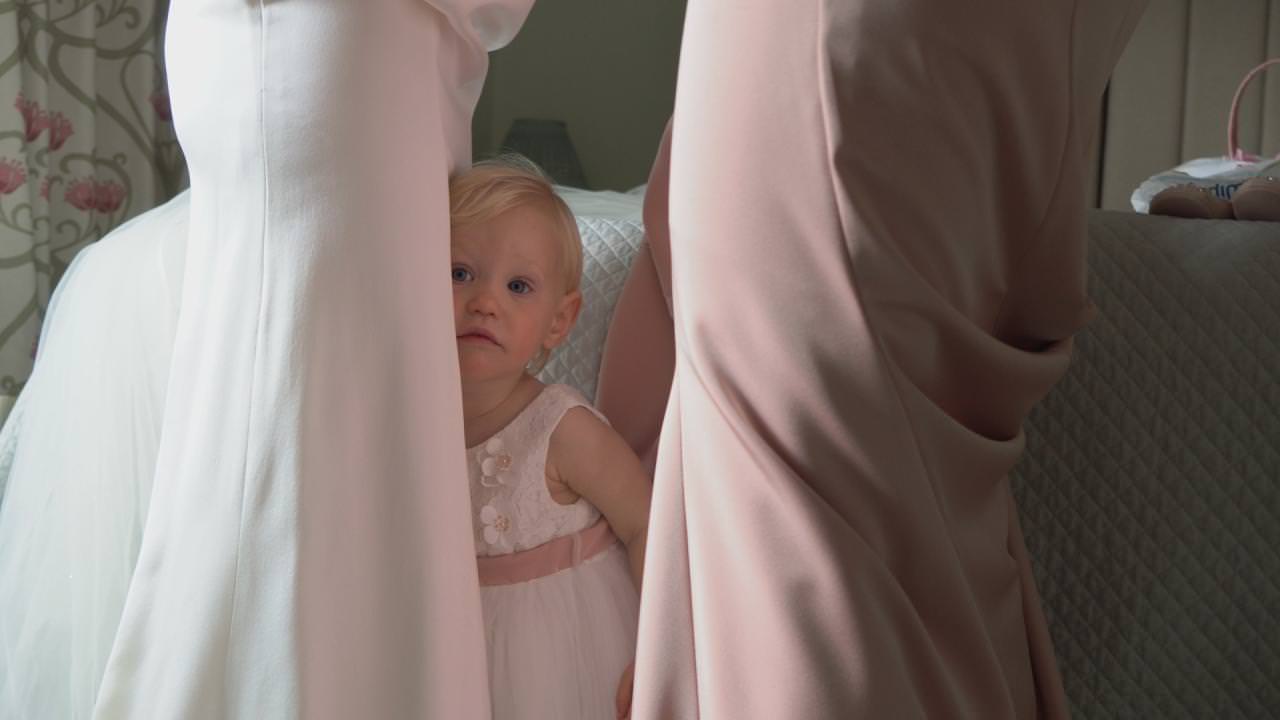 blonde toddler flower girl standing between the bride and bridesmaid during bridal prep