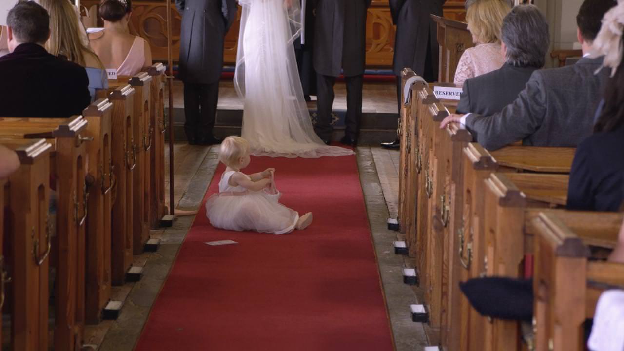 a flower girl sits on the carpet during a wedding ceremony at St Marks