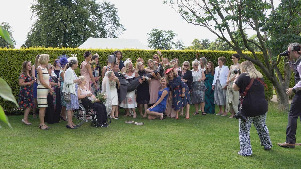 a large fun wedding group photo on the lawns of dunham massey