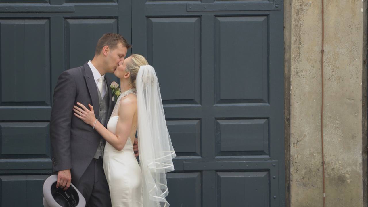 a posed wedding kiss outside grey Dunham Massey doors