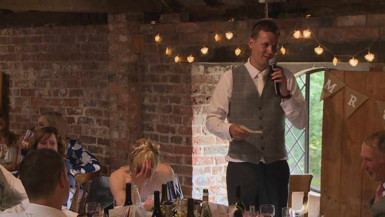 a bride holds her head in her hand during the grooms speech