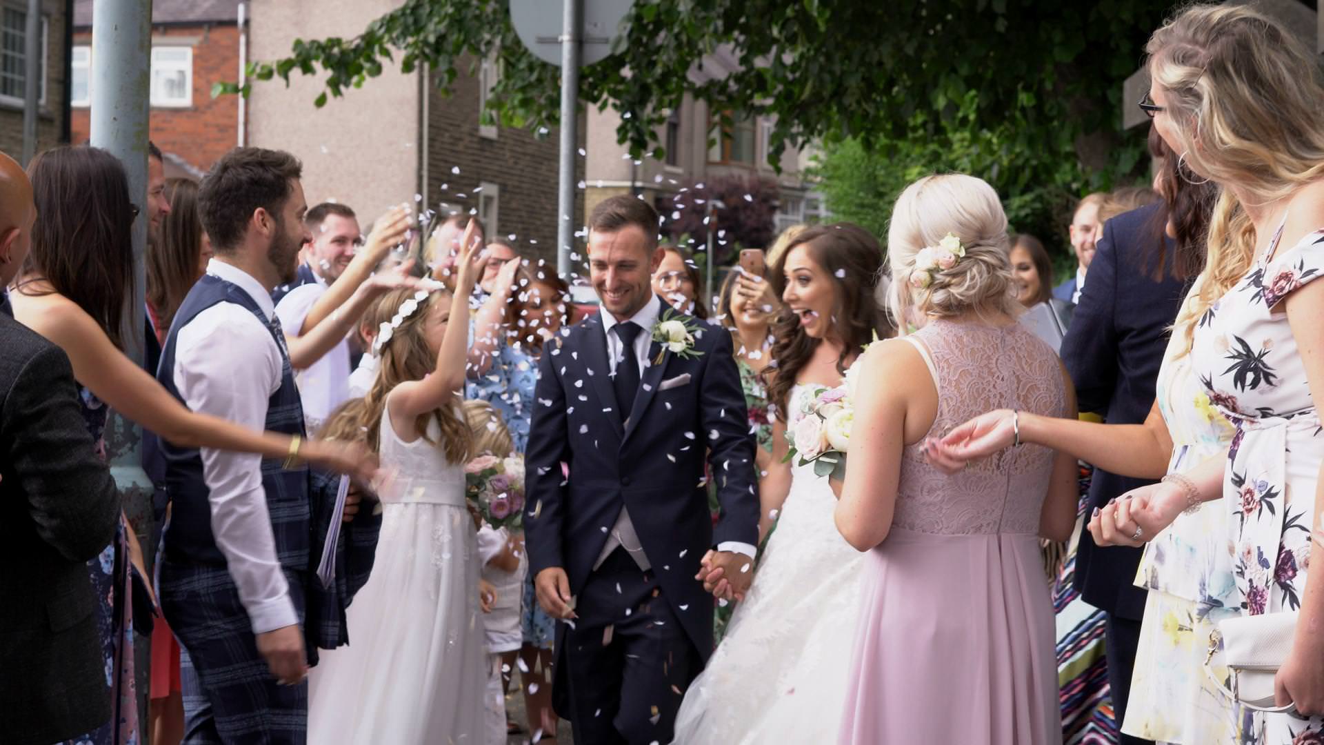 a bride a groom laugh as they get showered in Dollz confetti during a Lancashire wedding