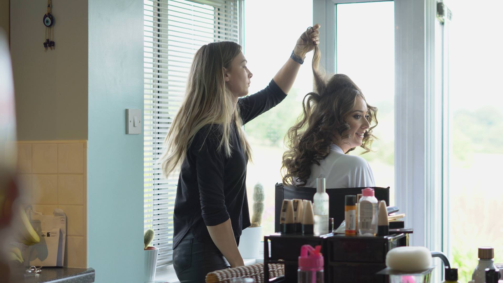 a bride gets her hair done at home before her wedding