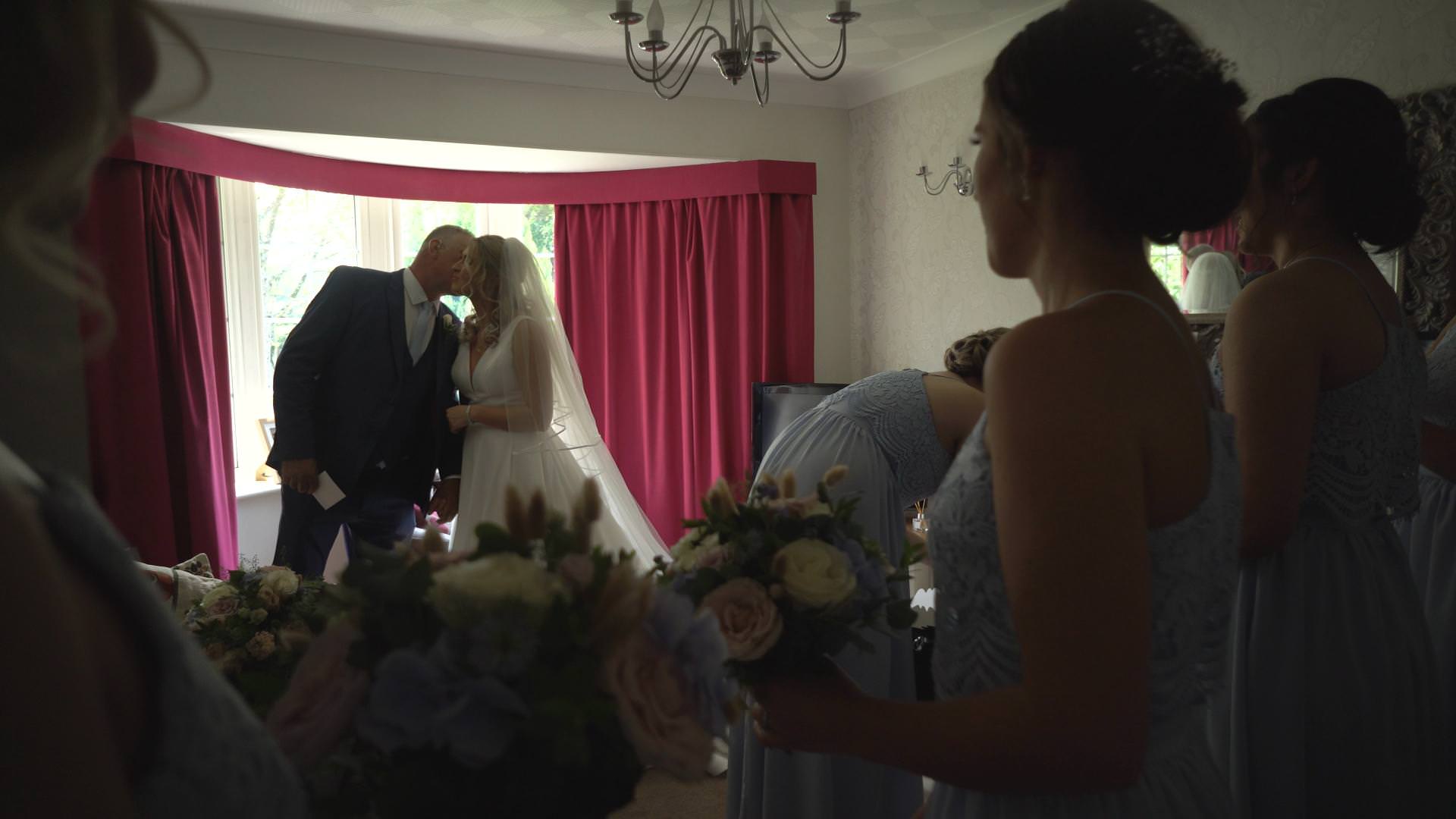 a video still of dad kissing the bride before they leave for church