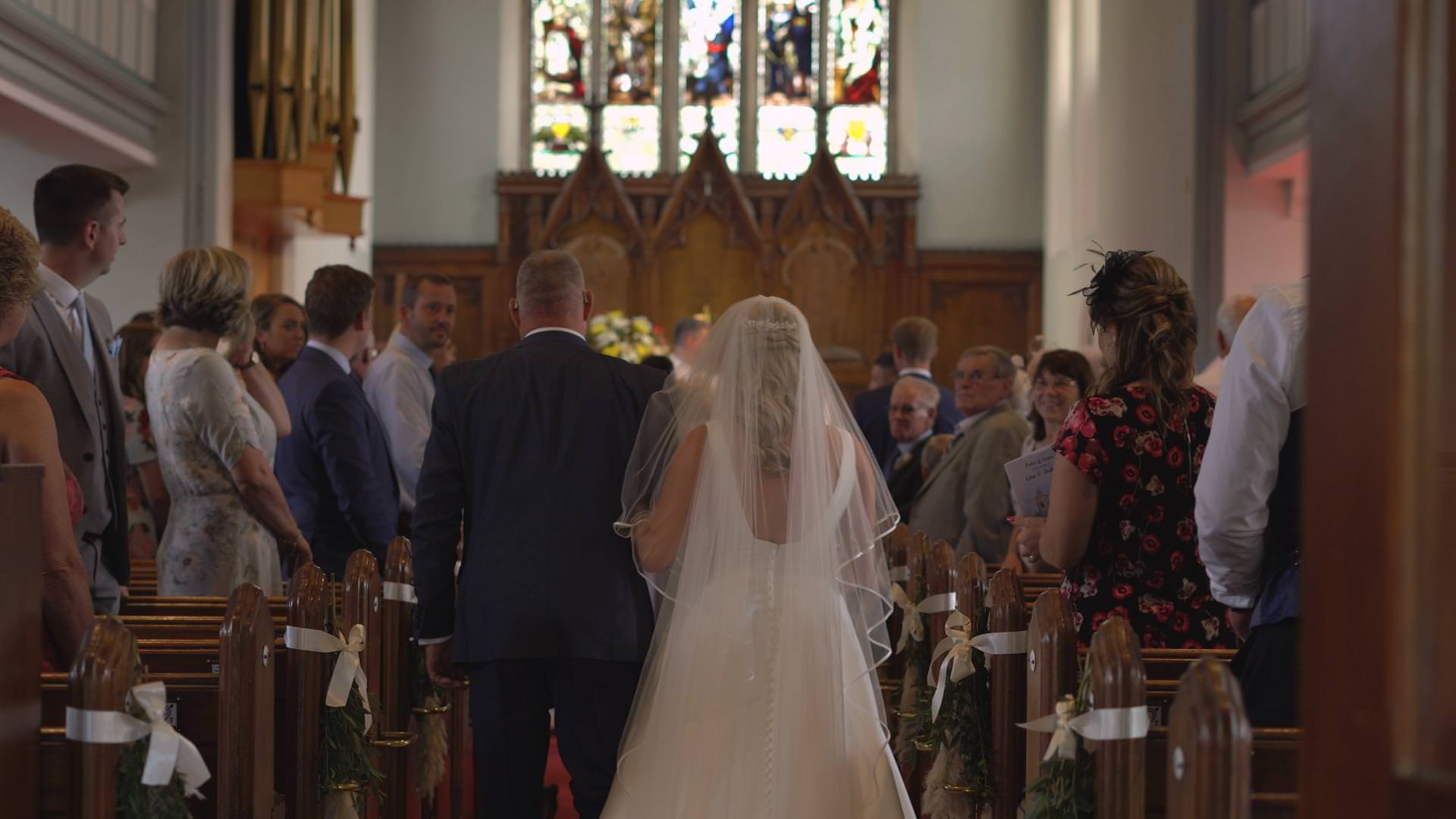 a video still of a bride walking down the aisle at St Johns church in Burscough