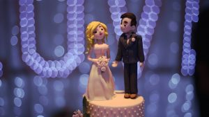 a close up video still of a fun wedding cake topper