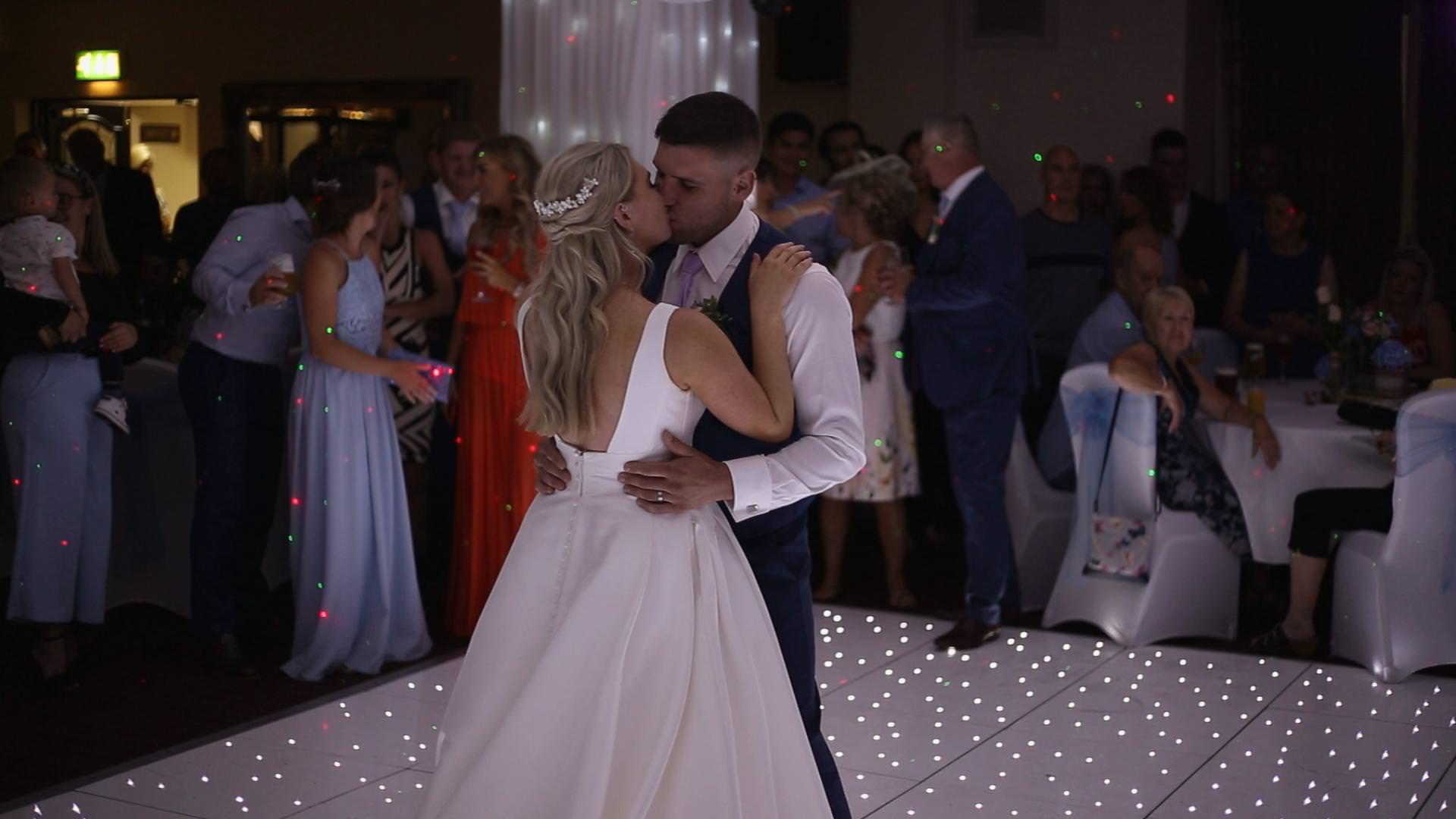 a bride and groom kiss on a sparkly dance floor at briars hall