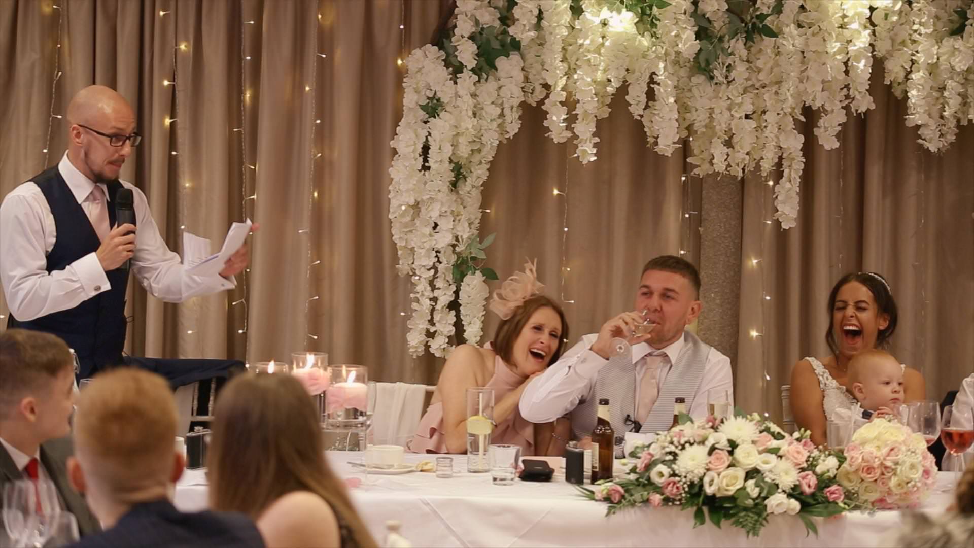 a video still of the top table during the wedding speeches at moddershall oaks