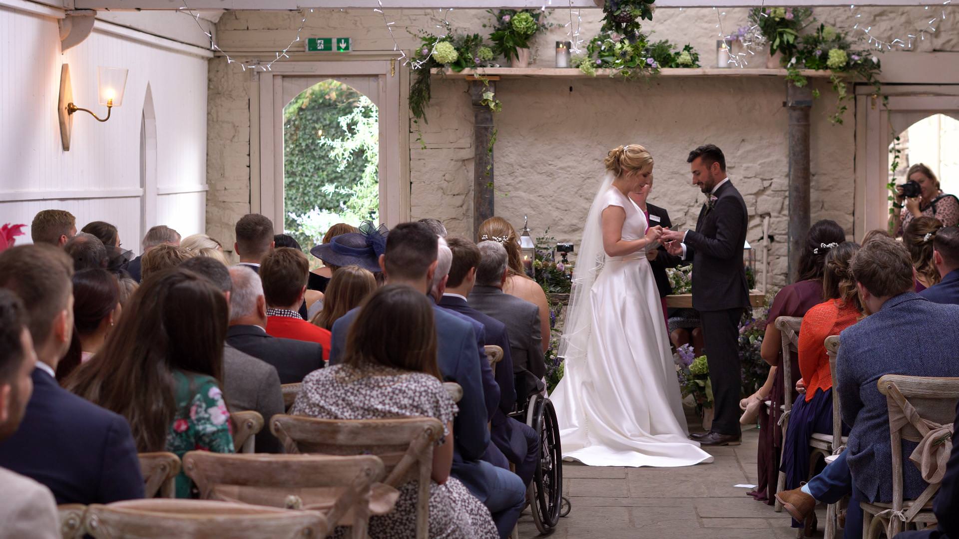 a bride and groom exchange rings in the ceremony barn at Wyresdale
