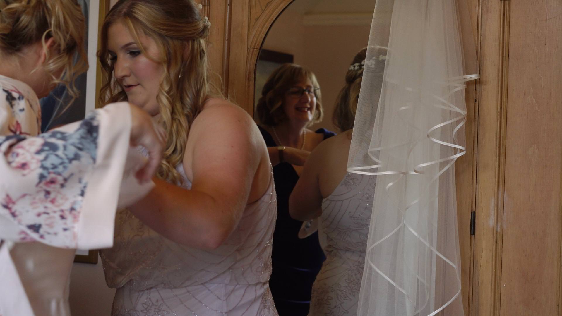 video of a mirror reflection of a bride getting in to her dress