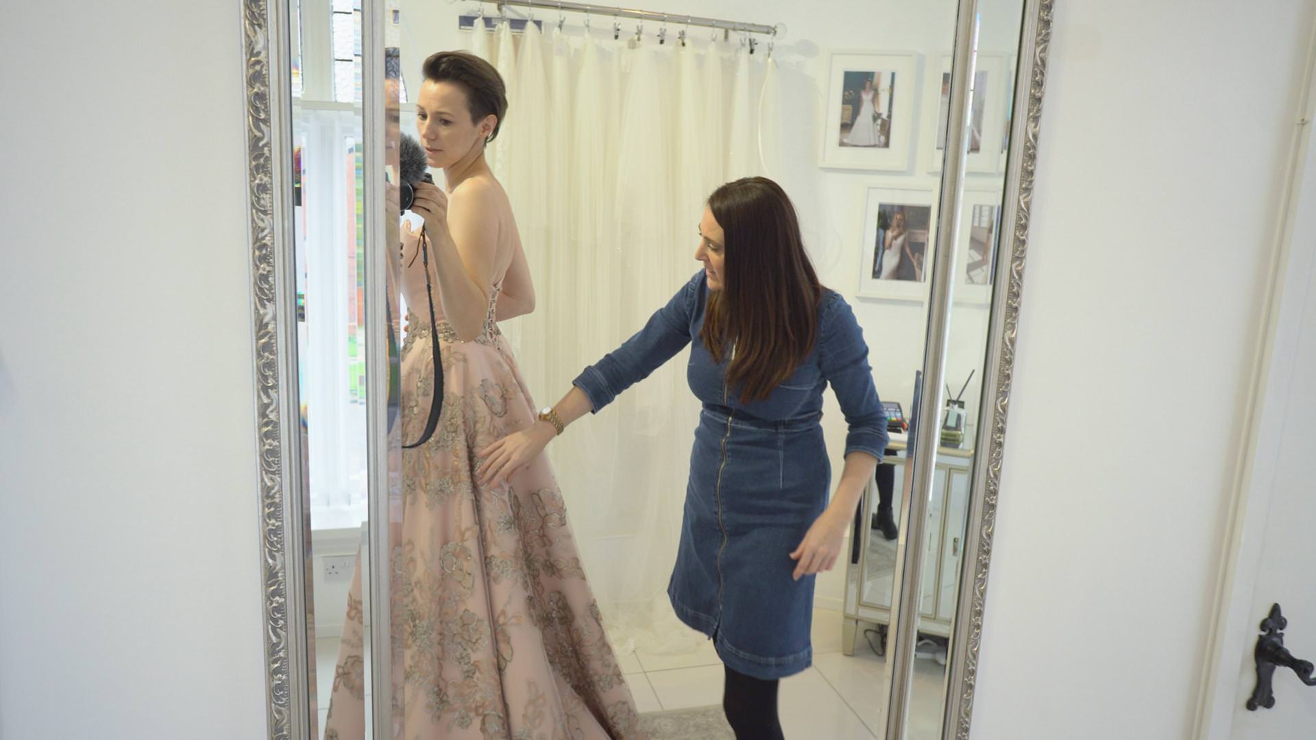 clare suzanne checks the fit of a wedding dress on a bride to be for a vlog