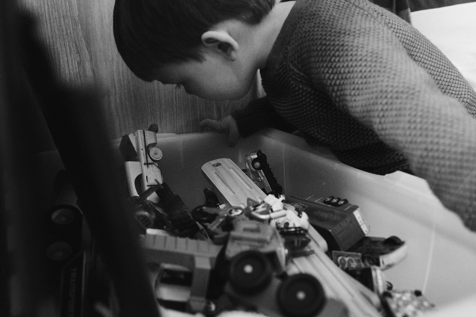 black and white photo of son looking in toy box