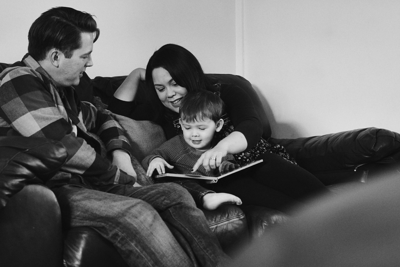 relaxed photo of mum dad and son snuggle on the sofa to read a book