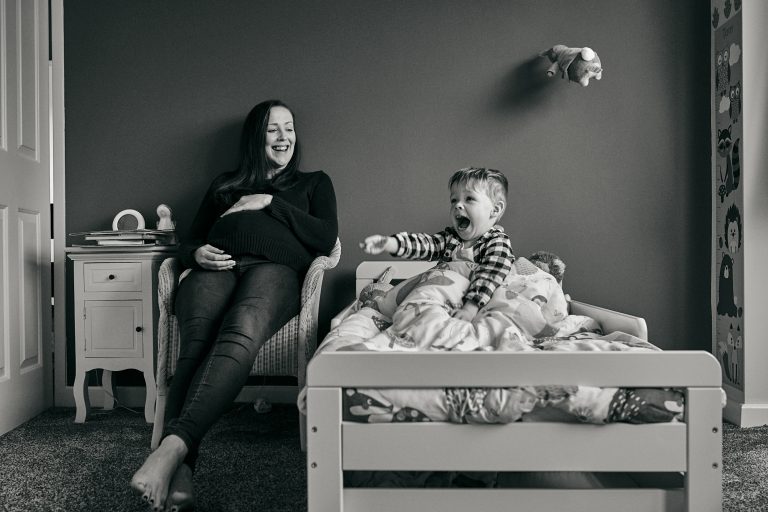 fun photo of pregnant mum and older son laughing in Cheshire family shoot