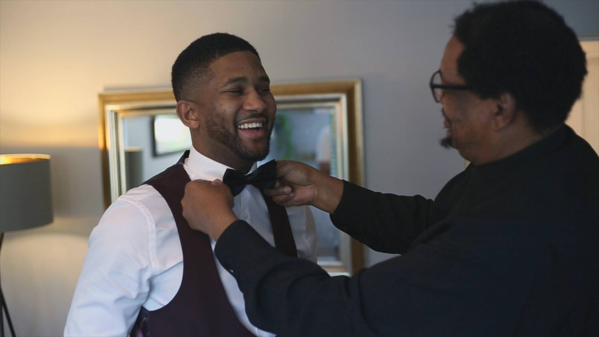 someone helps groom with his black bow tie before winter wedding in preston