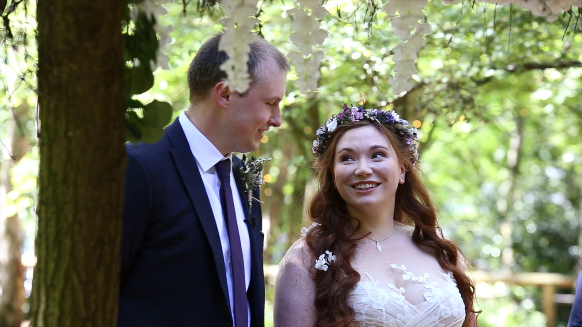 bride looks up and smiles at groom during outdoor ceremony