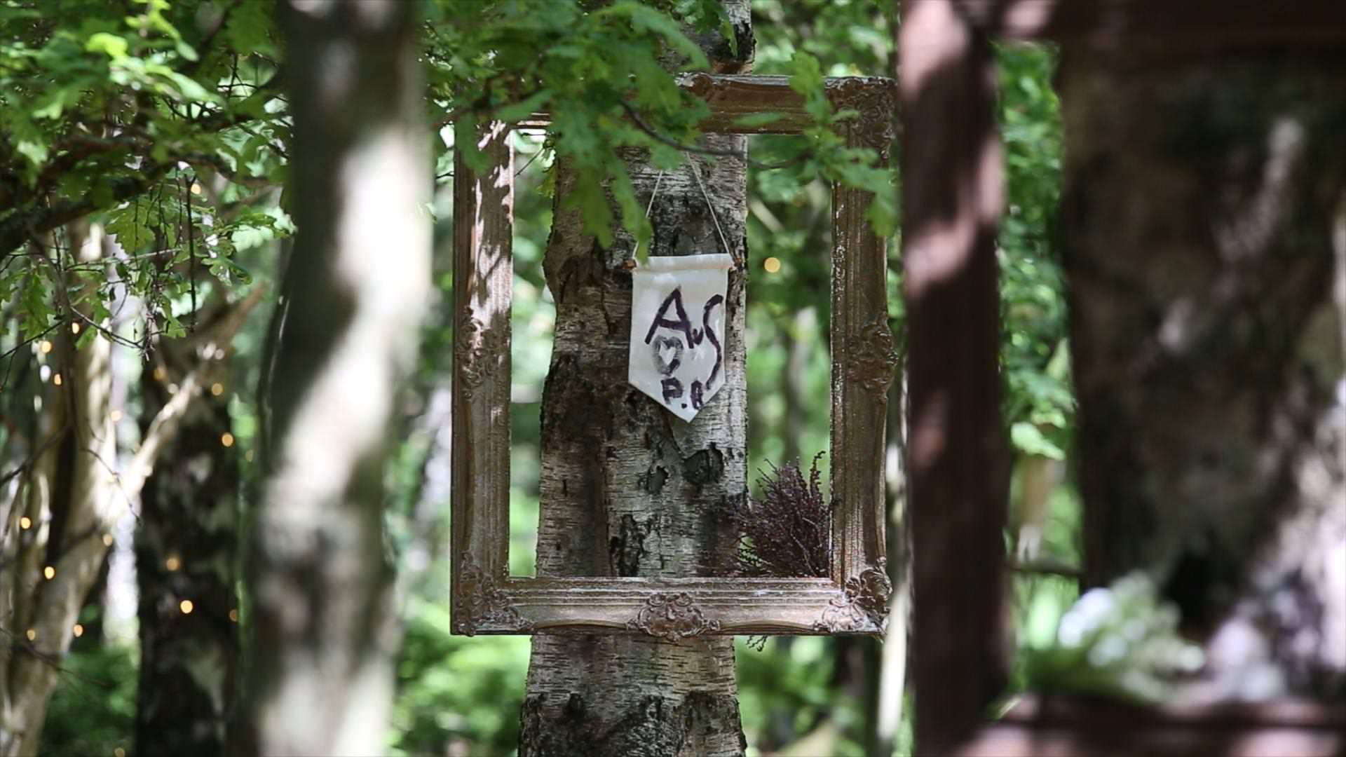 couple initials hanging at woodland wedding ceremony