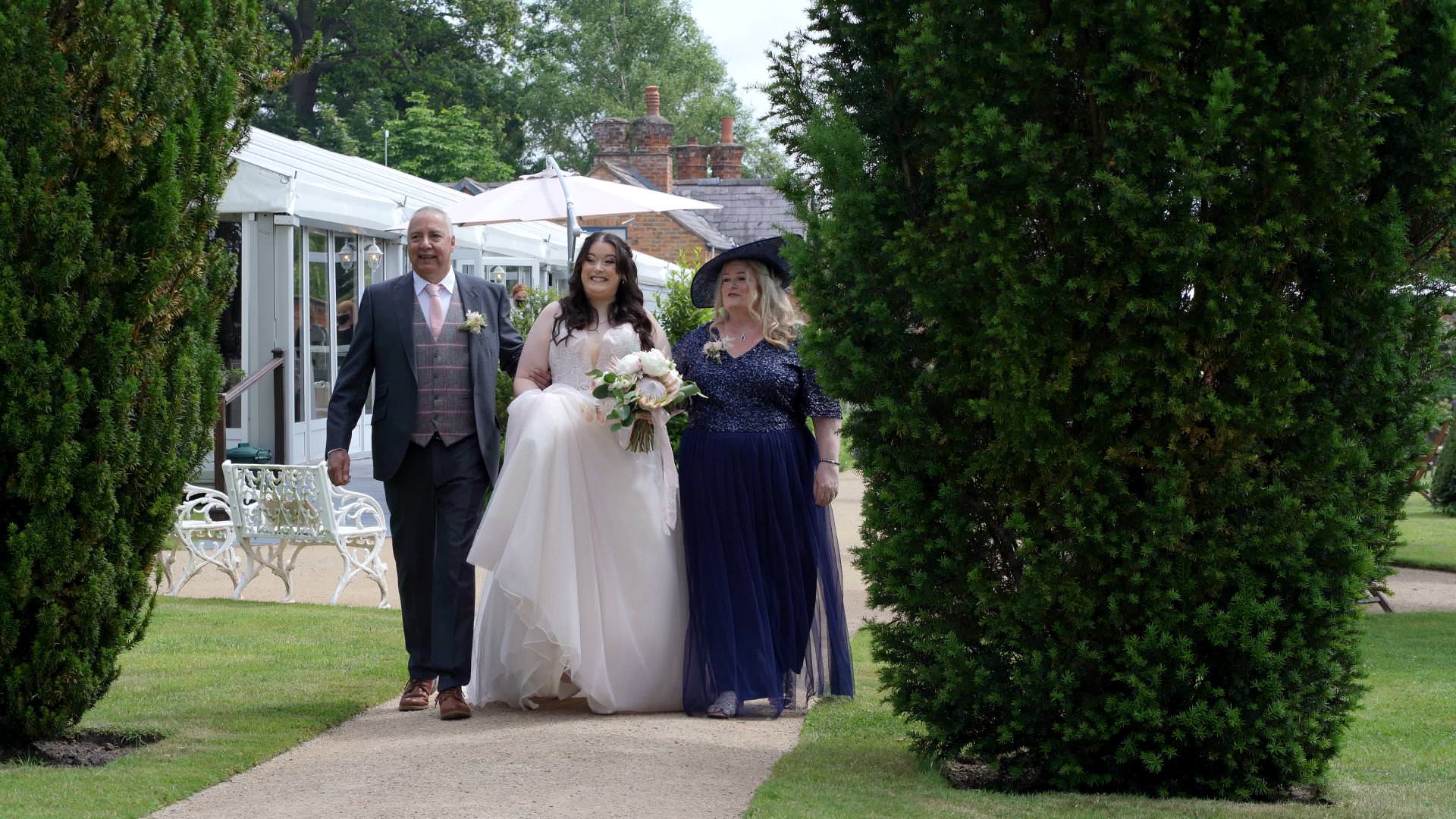 bride walks with dad and mum down aisle