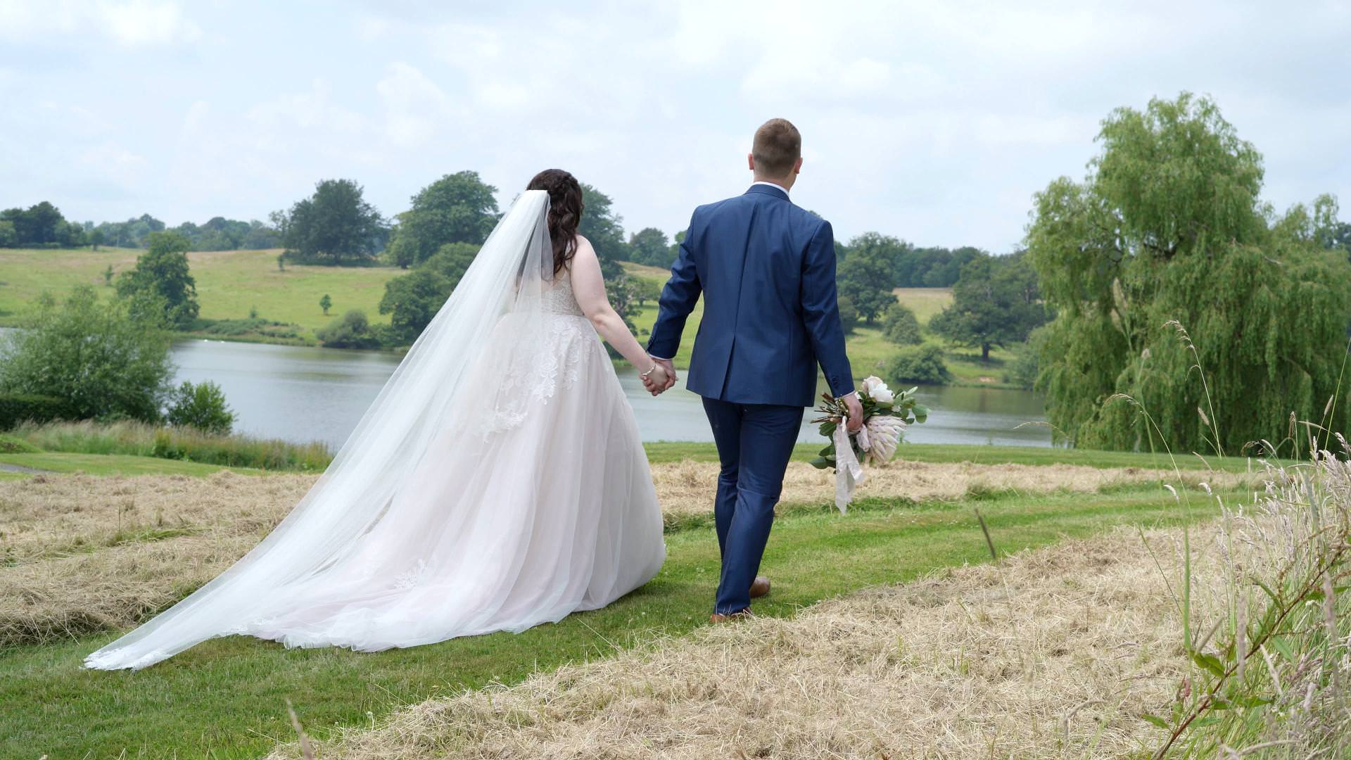 couple walk by lake at Combermere Abbey