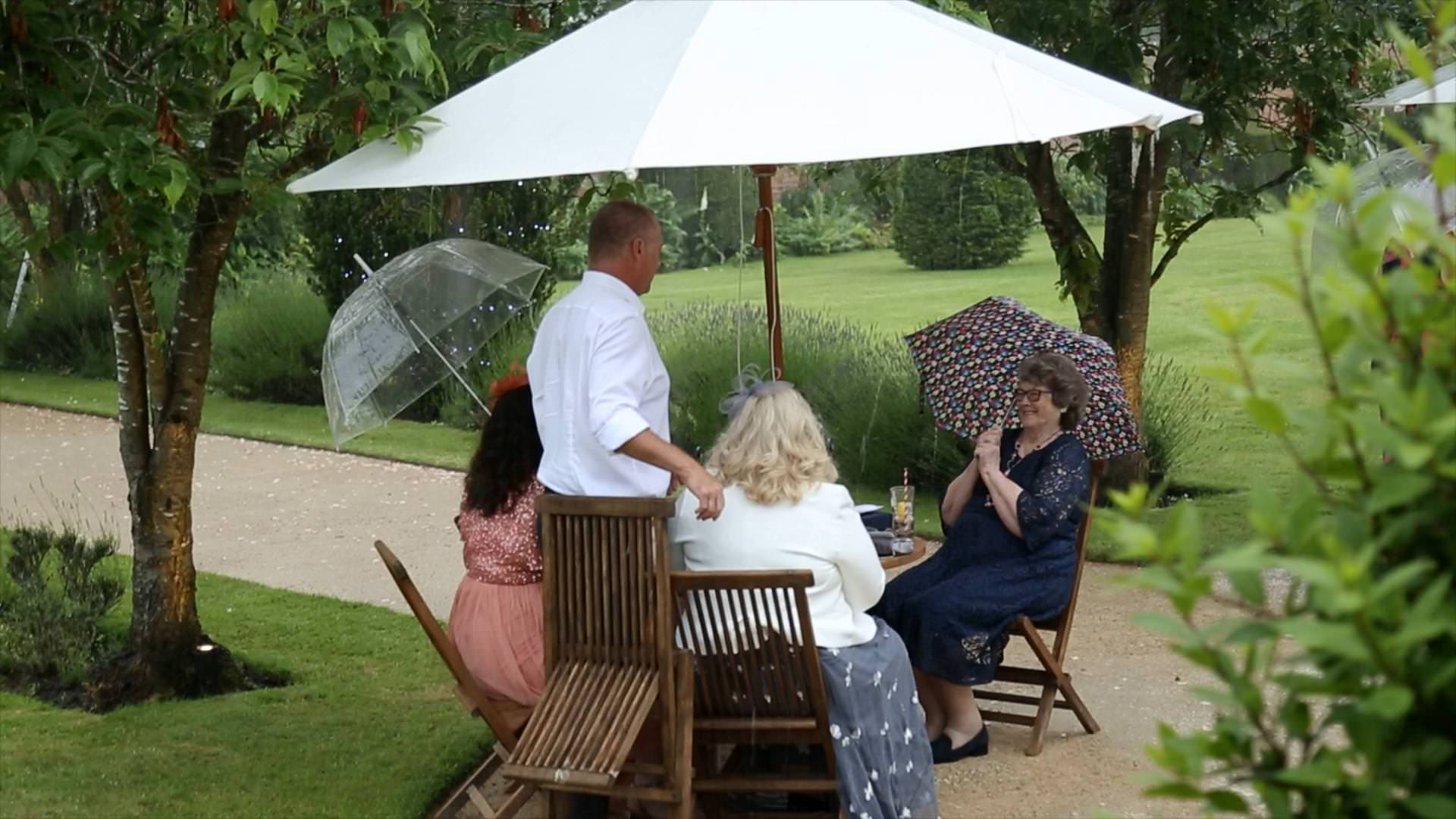 guests hide under cover from the rain during wedding